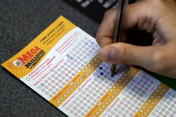 A customer fills out a Mega Millions ticket at a co<em></em>nvenience store on Tuesday in Northbrook, Ill. 
