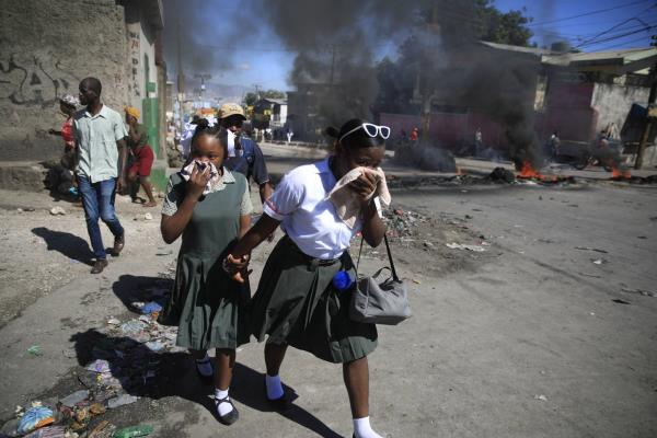 Students walk past a burning barricade that was set up by members of the police protesting bad police governance in Port-au-Prince, Haiti, Thursday, Jan. 26, 2023. 