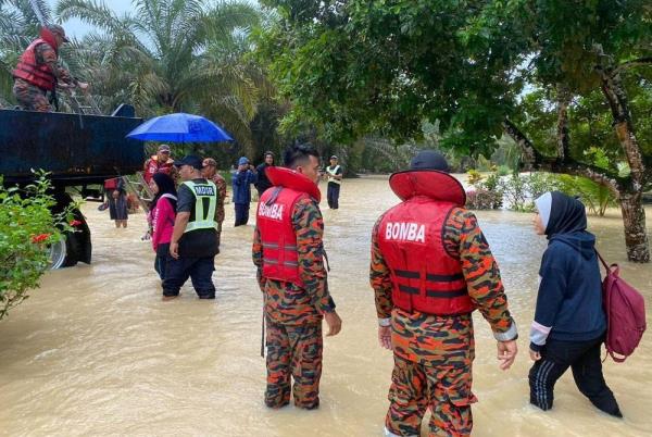 Flood victims in Kampung Sri Rambai Machap, Simpang Renggam escorted to the PPS by firemen on Wednesday.