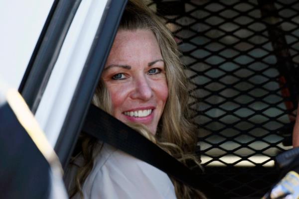 Lori Vallow Daybell smiles from the back of a police car. 