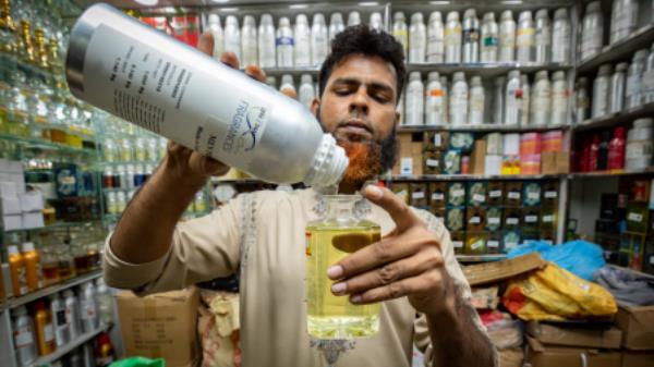 A shopkeeper is showing a customer one of the most expensive items of perfume in the Mitford area in Old Dhaka. Noor-A-Alam