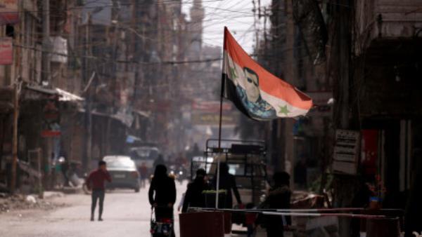  A natio<em></em>nal flag depicting a picture of Syria's President Bashar al-Assad flutters at a checkpoint in Douma, in the eastern suburbs of Damascus, Syria March 10, 2021. Picture taken March 10, 2021. REUTERS/Omar Sanadiki/File Photo