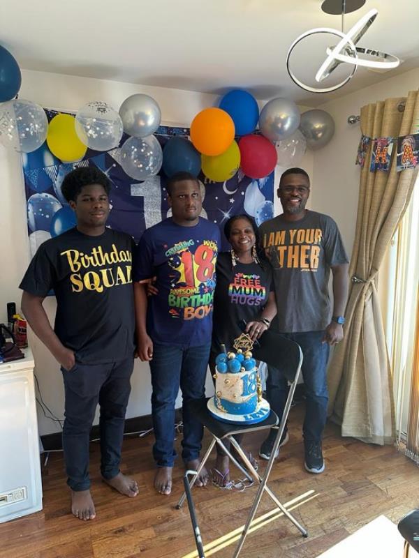 Anthony and Abi with both sons at Levi's birthday, standing in front of his birthday cake at home