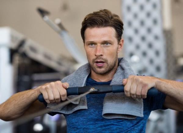 fit man on rowing machine demo<em></em>nstrating exercise habits for strong forearms