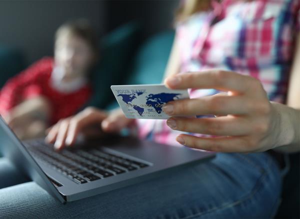 woman holding credit card o<em></em>nline shopping laptop