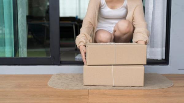 Close up woman receiving goods in front of the house. Delivered parcel on door mat