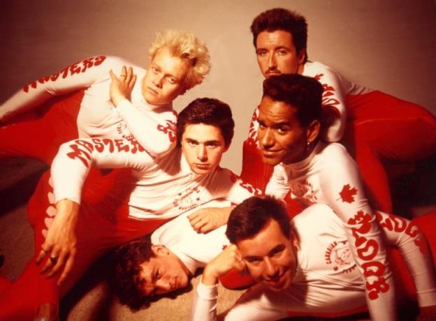 A group of six young men poses for the camera, wearing red pants and white shirts with  'Floor Masters' in red writing printed on the arms.