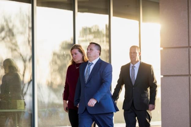 Two men and a woman walk near a courthouse.
