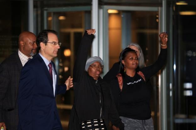 Two women hold up their fists outside a courthouse.