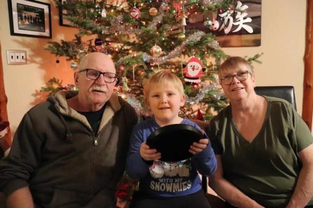 Maureen and Greg McBratney along with their grandson in front of their Christmas tree. 