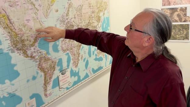 A man points his finger at a map to a location in Ontario.
