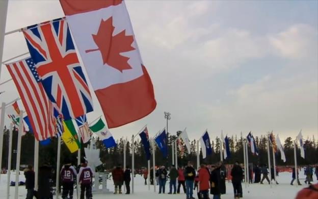 A bunch of people standing around tall flag poles with world flags on them