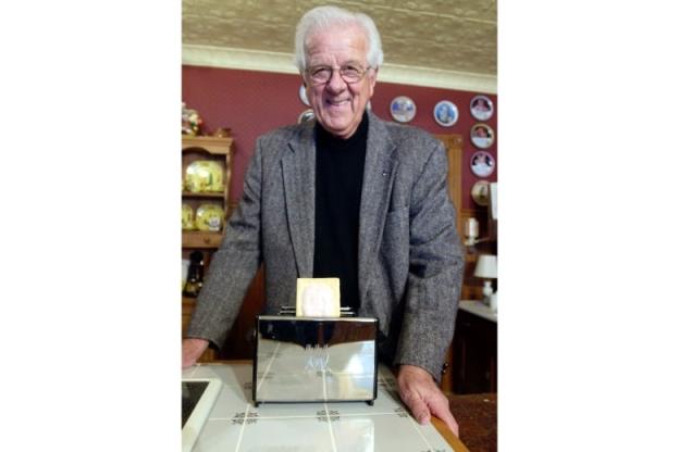 A man standing over a toaster co<em></em>ntaining a Pop Tart.