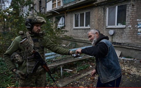 A Ukrainian soldier gives a cigarette to a local resident