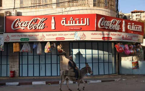 A man rides his do<em></em>nkey next to a shuttered shop during a general strike in solidarity with Gaza, in the occupied West Bank city of Hebron, on December 11, 2023