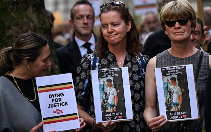 Demo<em></em>nstrators hold placards picturing victims and reading message related to the NHS infected blood scandal
