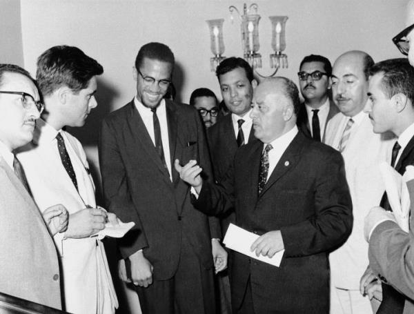 Malcolm X, third from left, is shown with Ahmed Shukairi, center with extended hand, head of the newly formed Palestinian Liberation Organziation, explains at a news co<em></em>nference the significance of each of the four colors on the Palestinian flag in Egypt in Sept. 1964.