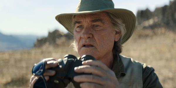 Lee Shaw holds up a pair of binoculars in Mo<em></em>narch Legacy of Monsters
