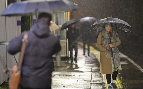 Commuters attempt to shelter during heavy rain at Maze Hill Station in Greenwich south east London