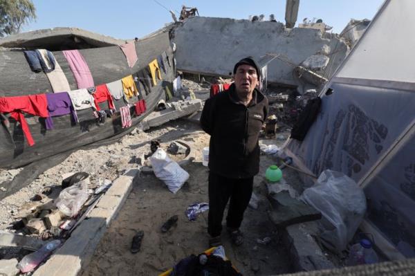 A displaced Palestinian man stands in a tent encampment for displaced people in Gaza