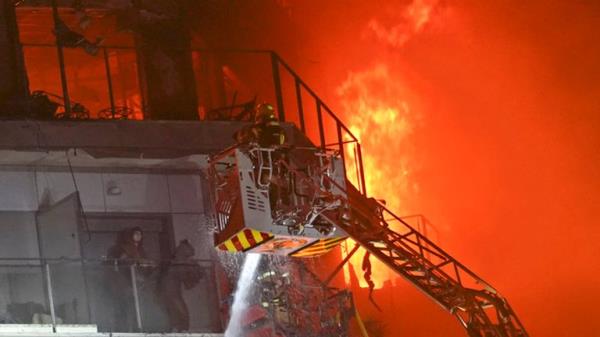 Firefighters rescue two people trapped on a balcony. Pic: AP