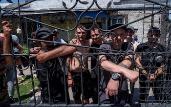 Priso<em></em>ners stand behind the fence in the barrack's yard in a prison in the Dnipropetrovsk region, Ukraine