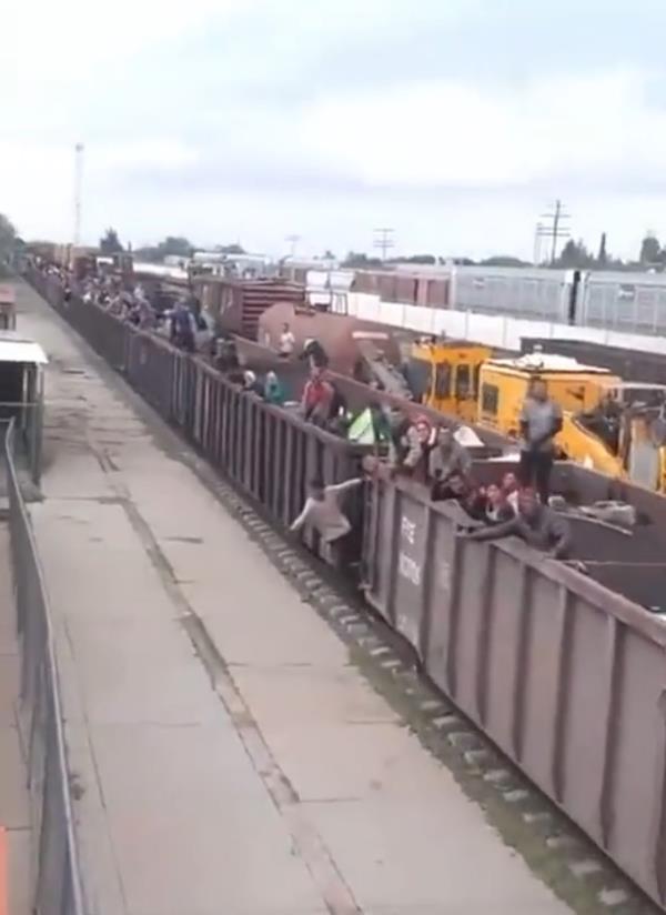 A screengrab from the video showing migrants hanging off the sides of the cargo train.