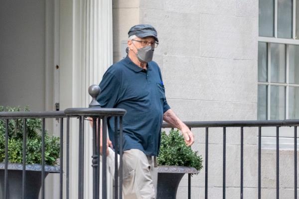 Robert De Niro walks out of building entrance. 