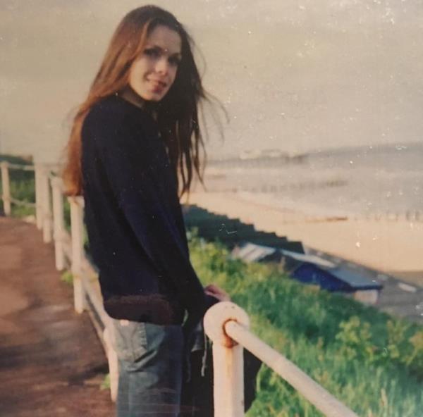 Juliette Burton as a teenager standing in front of a beach