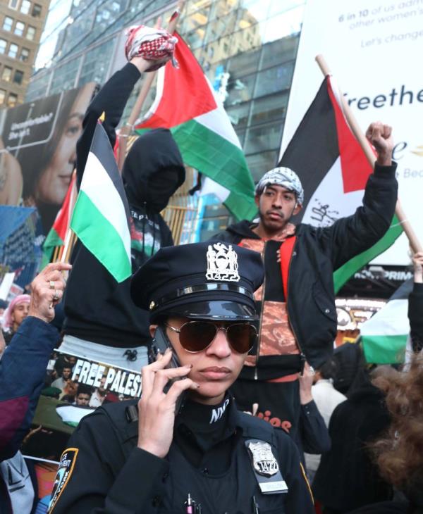 A police officer with Pro Palestinian protesters is seen in Times Square on Oct. 13, 2023.