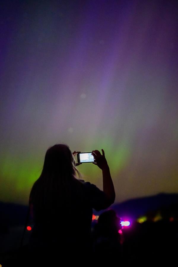 Woman photographing spectacular Northern Lights at Chanticleer Point Lookout, Columbia River Gorge, Oregon