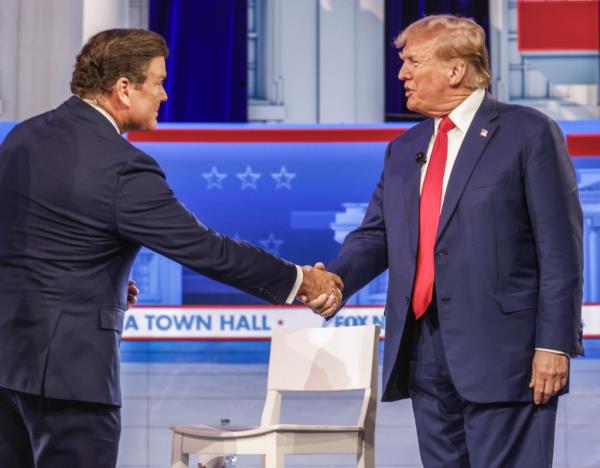 Former US President Do<em></em>nald J. Trump (R) shakes hands with Fox News journalist Bret Baier as he arrives to participate in a Fox News Town Hall event at the Iowa Events Center in Des Moines, Iowa, January 10, 2024.