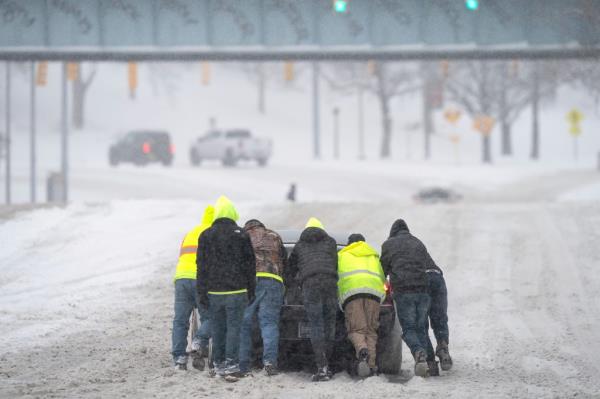 People help a driver out after his rear-wheel drive vehicle got stranded after a winter storm in Nashville, Tenn.