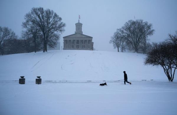 Billie, a beagle-mix, leads the way for owner Brandon Crooks of Nashville as they walk near the Tennessee State Capitol after a winter storm in Nashville, Tenn., Monday, Jan. 15, 2024