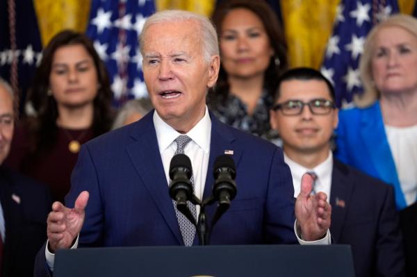 President Joe Biden speaking at a podium during the 12th anniversary of the Deferred Action for Childhood Arrivals program event, in the East Room of the White House with Vero<em></em>nica Escobar and Nanette Barragán in the background.