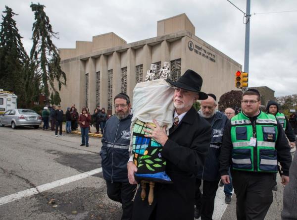 Security and religious leaders carrying Torah wrapped in cloth from synaogogue.