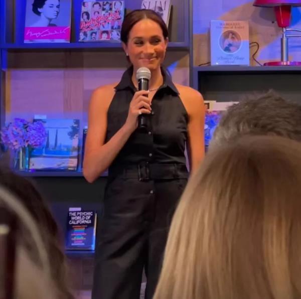 Meghan Markle holding a microphone during a surprise appearance at the grand opening of Godmothers bookstore in Summerland, California