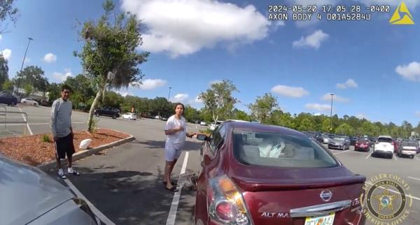 A woman stands near the car in question. 