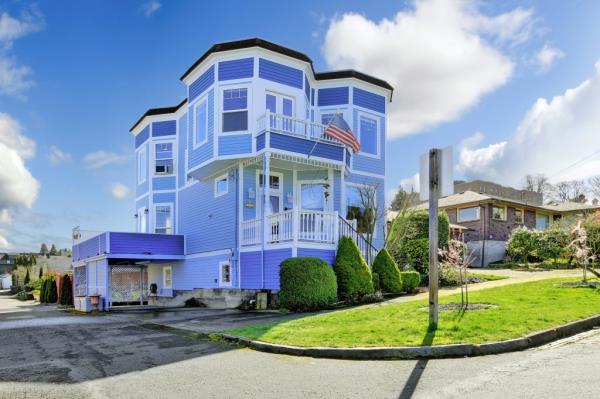 Light blue house with a front porch and American flag