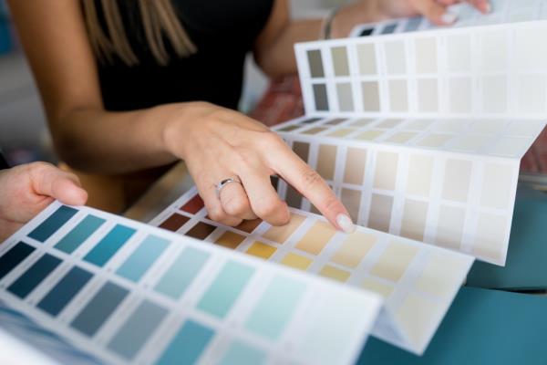 Two women discussing wall paint options, one pointing at a color chart