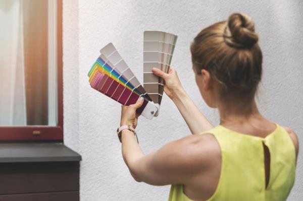 Woman holding a color swatch, choosing paint for house exterior facade