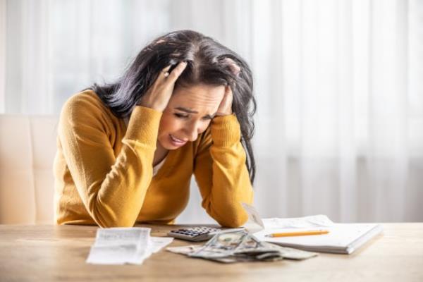 Upset young woman looking at her shopping receipt and shocked at the price.