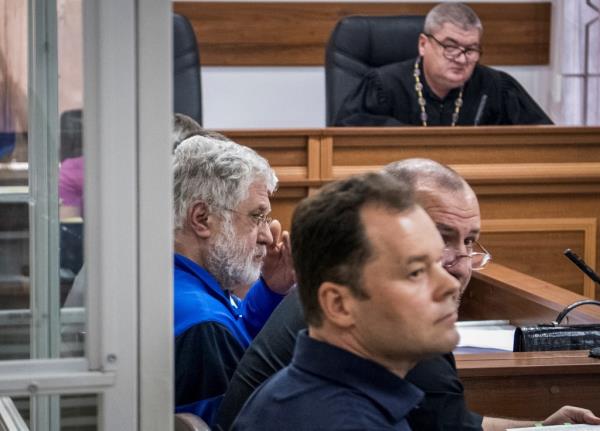 Igor Kolomoisky sits in a courtroom with two other men next to him and a judge in the background.