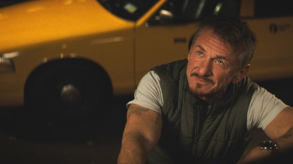 Sean Penn looks up with a yellow cab behind him in a 