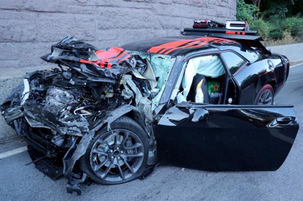 Mangled wreck of a black Dodge Challenger with red stripes after a fatal head-on crash on Henry Hudson Parkway