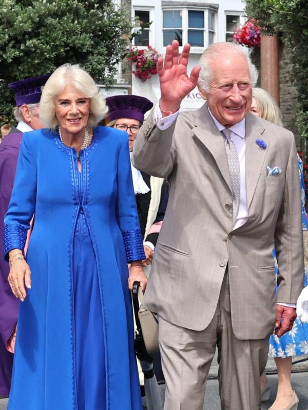 King Charles III and Queen Camilla in blue dress and grey suit, arriving at Guernsey with excited crowds in the background