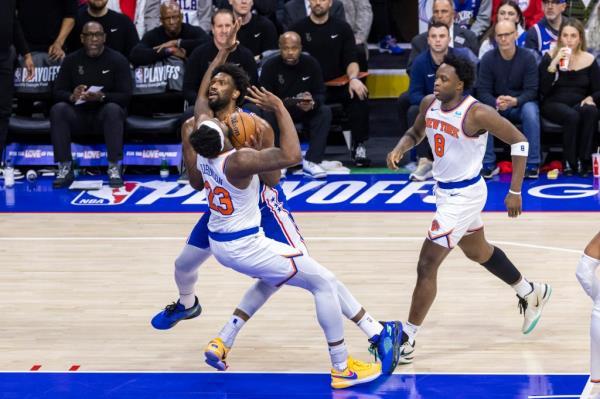 Mitchell Robinson of the New York Knicks drawing a foul as Joel Embiid of the Philadelphia 76ers drives into him during a basketball game