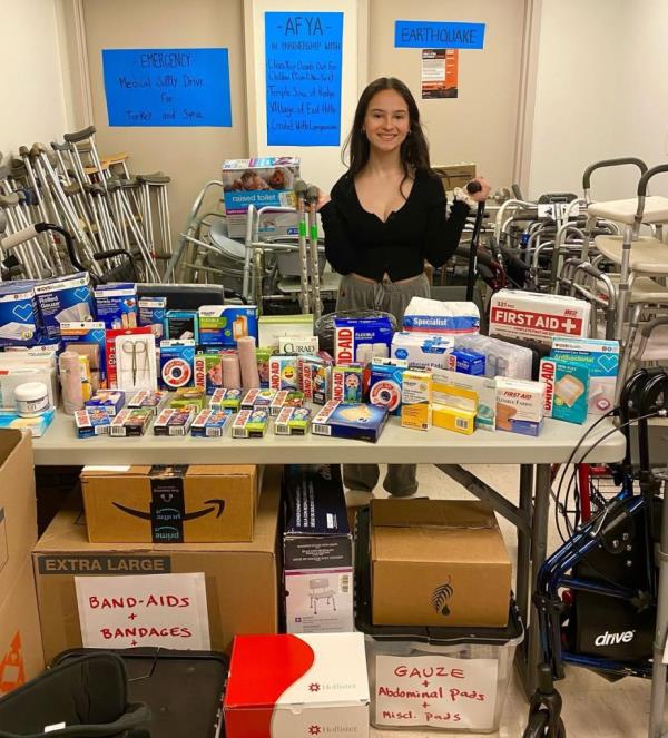 Teenage girl standing in front of a cart filled with toys and medical supplies for do<em></em>nation to pediatric cancer patients