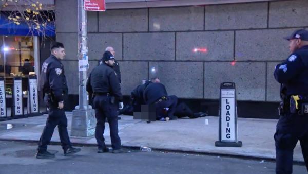 The victim's body is pixelated as police try to save him on the side of the street