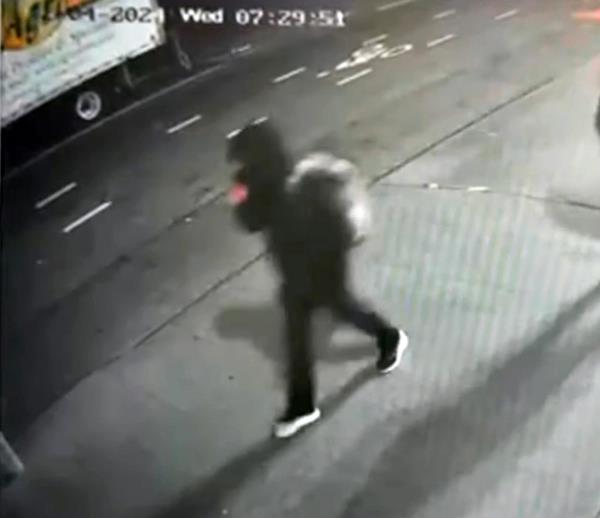 The suspect walks down the street in dark clothing and a backpack, as seen in CCTV footage